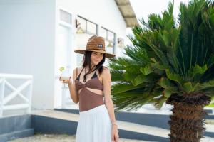 a woman wearing a hat standing next to a palm tree at Amotape Hotel in Zorritos +10 photos