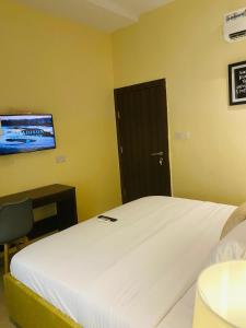a bedroom with a bed and a tv on a wall at KIFA Stays in Laniya