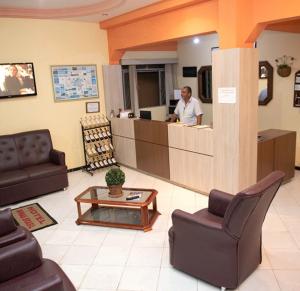 a man standing at the counter of a waiting room at Hotel Minas Brasil in Salinas