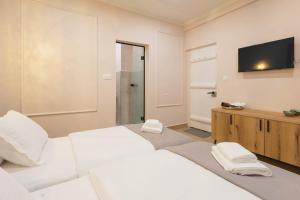 a bedroom with a white bed and a flat screen tv at Mihail Residence - Old Town of Kavala in Kavála