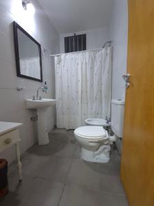 a white bathroom with a toilet and a sink at Rincón del Sol en Albardón in Albardón +11 photos