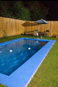 a blue swimming pool in a yard with an umbrella at Atahualpa Yupanqui 2 in Tafí del Valle