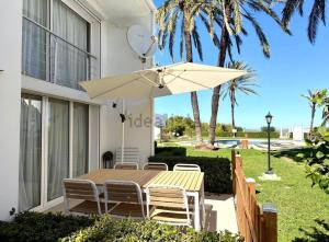 a table and chairs with an umbrella on a patio at Precioso bungalow con piscina en 1a Linea Playa in Denia