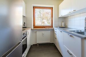 a kitchen with white cabinets and a window at Bergluft in Bad Hindelang