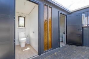 a bathroom with a toilet and a window and a door at Beachside on Hinemoa in Whangamata +21 photos