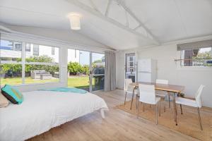 a bedroom with a bed and a table and chairs at Beachside on Hinemoa in Whangamata