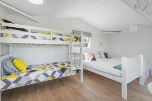 two bunk beds in a white room with wood floors at Beachside on Hinemoa in Whangamata