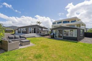 a house with a yard with a couch and a house at Beachside on Hinemoa in Whangamata