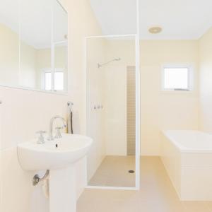 a white bathroom with a sink and a shower at Modern 2BR Townhouse with BBQ & Pool Access in Muswellbrook +2 photos