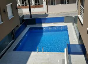 an overhead view of a blue swimming pool next to a building at Blue Sea Nest in Paralia Katerinis