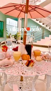 a table with plates of food and an umbrella at Pousada Villa Monale in Barreirinhas