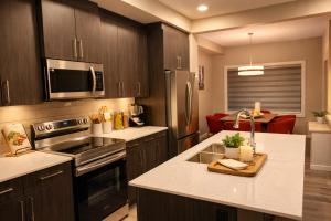 a kitchen with wooden cabinets and stainless steel appliances at NorthEdge Suites Leduc in Leduc