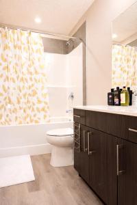 a bathroom with a toilet and a shower curtain at NorthEdge Suites Leduc in Leduc