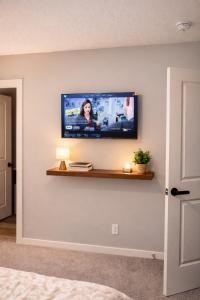 a flat screen tv on a wall in a bedroom at NorthEdge Suites Leduc in Leduc