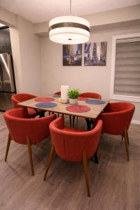 a dining room with a table and red chairs at NorthEdge Suites Leduc in Leduc +18 photos