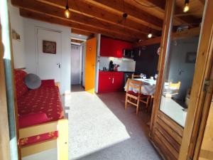 a living room with a red couch and a kitchen at Le Doux Refuge in Ustou