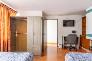 a bedroom with a bed and a desk and a television at Hospedaje Sary House in Bogotá