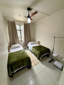 a bedroom with two beds and a ceiling fan at Angra Prime Centro in Angra dos Reis