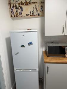 a white refrigerator in a kitchen next to a counter at Zikach Apartment Near to Glasgow Airport in Renfrew