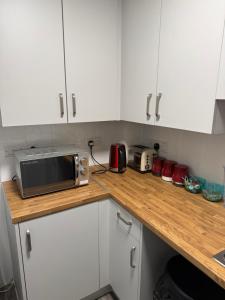 a kitchen with white cabinets and a microwave on a counter at Zikach Apartment Near to Glasgow Airport in Renfrew