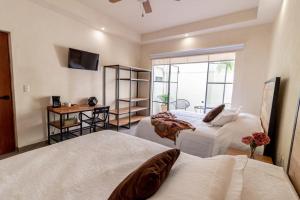 a bedroom with two beds and a desk and a television at Casa María Teresa Suites in León