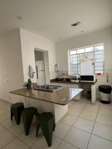 a large kitchen with a counter and green stools at Refugio Madalena Hostel in São Paulo