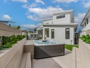 a white house with a hot tub in a backyard at Black Wattle Beach House in Casuarina