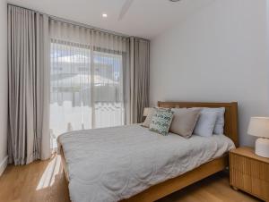a bedroom with a bed and a large window at Black Wattle Beach House in Casuarina