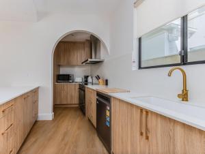 an open kitchen with wooden cabinets and a sink at Black Wattle Beach House in Casuarina