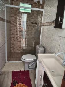a bathroom with a toilet and a shower and a sink at Ospedagem leão in Praia Grande