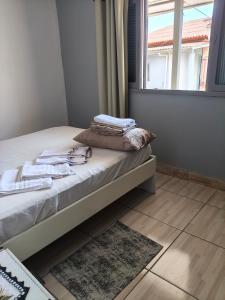 a bed with towels sitting on it in a room with a window at Ospedagem leão in Praia Grande