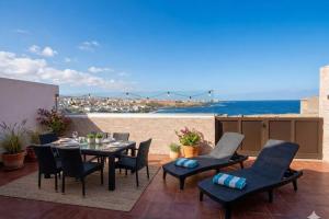 a patio with a table and chairs and the ocean at Sanmao Vibbecanarias Playa del hombre Telde in Playa del Hombre