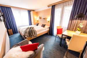 Habitación de hotel con cama, escritorio y sillas en Chalet Achat, en Zermatt