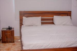 a bed with white sheets and a wooden headboard at Beulah House Lounge in Ibadan