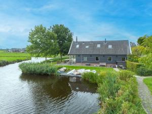 a house next to a river with boats in it at De Schuur in Kaag