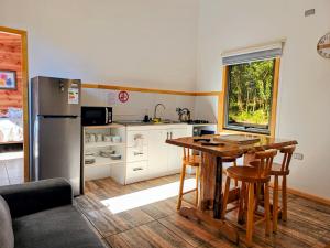 a kitchen with a table and a refrigerator at Cabañas Lagos y Volcanes in Coñaripe