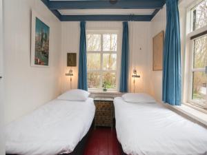two beds in a room with blue curtains and a window at Zandkamer in Vrouwenpolder
