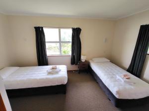 two beds in a room with a window at Te Ra Waitangi in Paihia