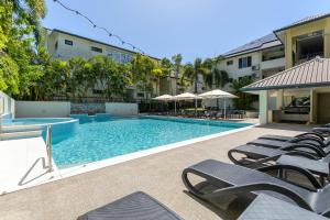 a swimming pool with chaise lounge chairs next to a building at Central Plaza Port Douglas in Port Douglas