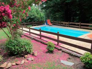 a swimming pool with pink flowers next to a fence at Cabañas Blumenhaus in Villa Ventana