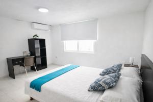 a white bedroom with a bed and a desk at Posada Lkjay Providencia Isla in Providencia