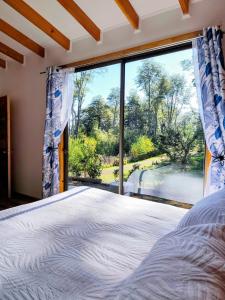 a bedroom with a large window and a bed at Cabañas Lagos y Volcanes in Coñaripe