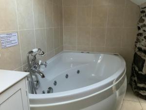 a white tub in a bathroom with a sign on the wall at Tithe Barn 1 - Abercelyn Cottages - Llanycil - Bala - Gwynedd - LL23 7YF - UK in Llanycil
