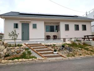 a white house with a green door and stairs at yucurum in Itoman