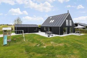 a black house with a playground in a yard at 30467-Odder-Ravnsager-15 in Odder