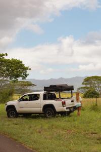 a woman is standing next to a white truck at Escape It All Rooftop Glamper fully equipped Tacoma in Anahola +4 photos