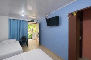 Ein Schlafzimmer mit einem Bett und einem Fernseher an einer blauen Wand in der Unterkunft Bread Fruit Lodge in San Andrés
