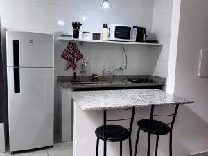 a kitchen with a counter with two stools and a refrigerator at Apartamento da Rosa Rua Epaminondas Otoni Número 777 in Teófilo Otoni +5 photos