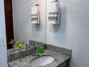 a bathroom with a sink and a mirror and towels at Apartamento da Rosa Rua Epaminondas Otoni Número 777 in Teófilo Otoni