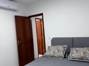 a room with a bed and a door and two pillows at Apartamento da Rosa Rua Epaminondas Otoni Número 777 in Teófilo Otoni